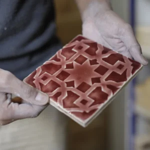 Worker of a handmade tile manufacturing company holding an artisanal tile